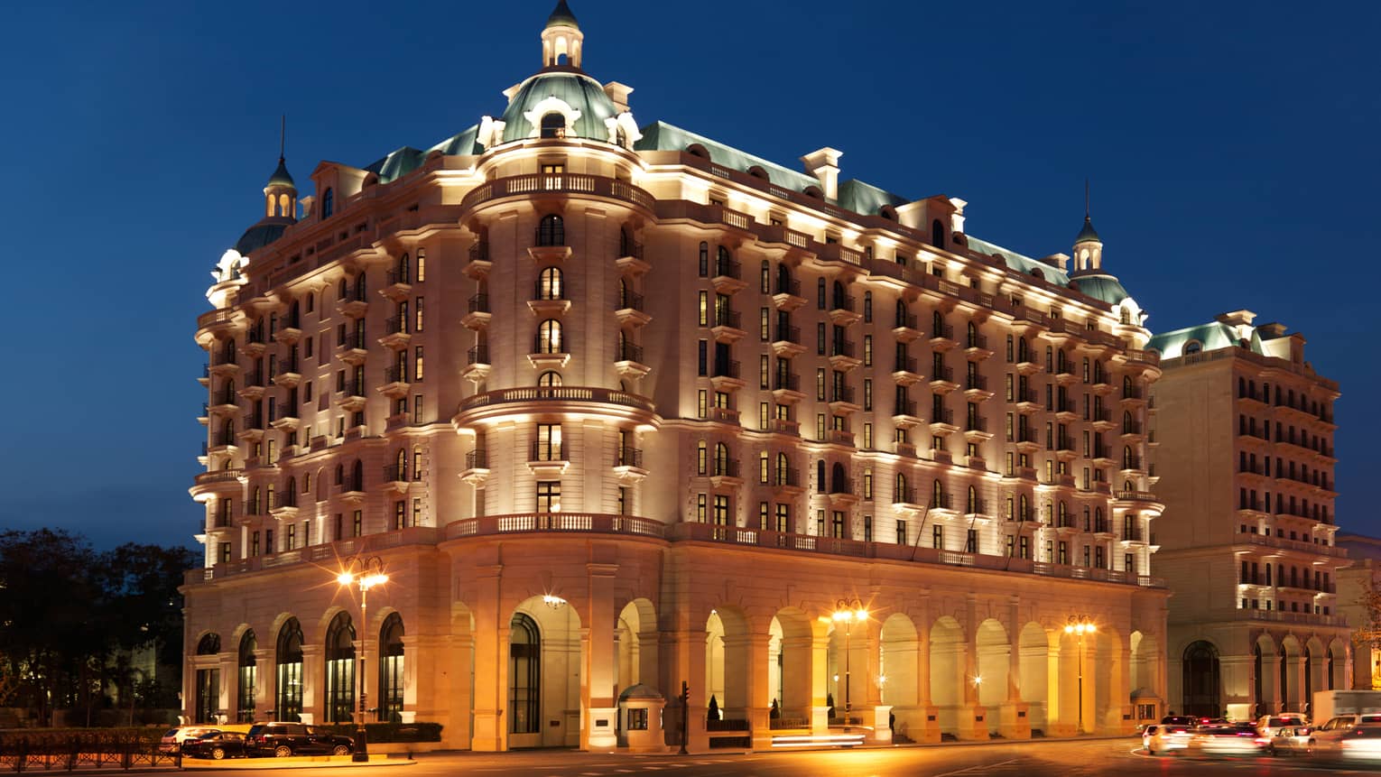 Night view of Baku Four Seasons Hotel Beaux-Arts-style building exterior with lights, illuminated roof