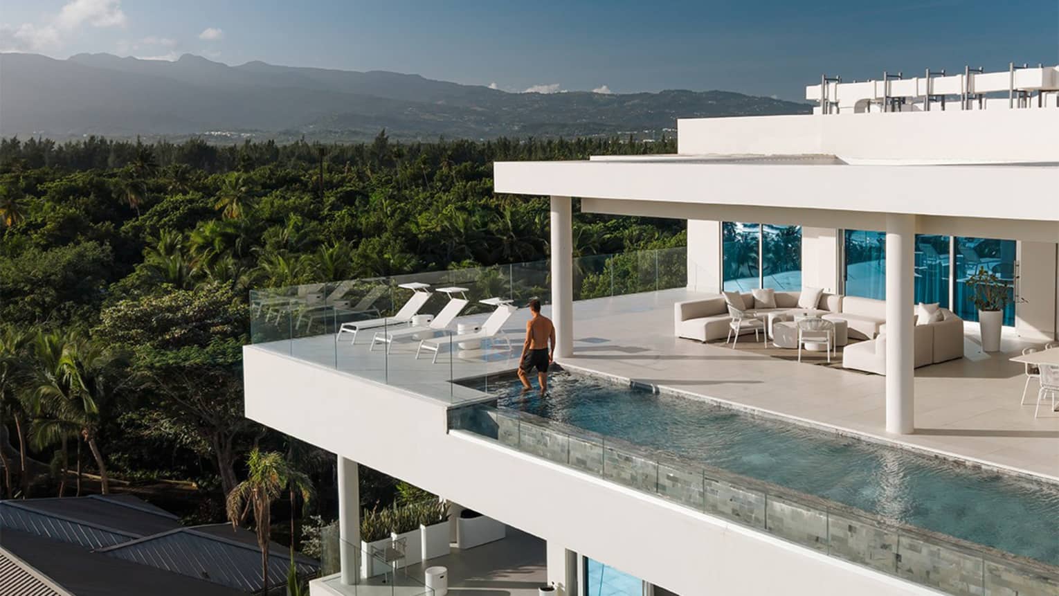 Modern multi-storey residence with infinity pool in tropical beach location with forest in the background