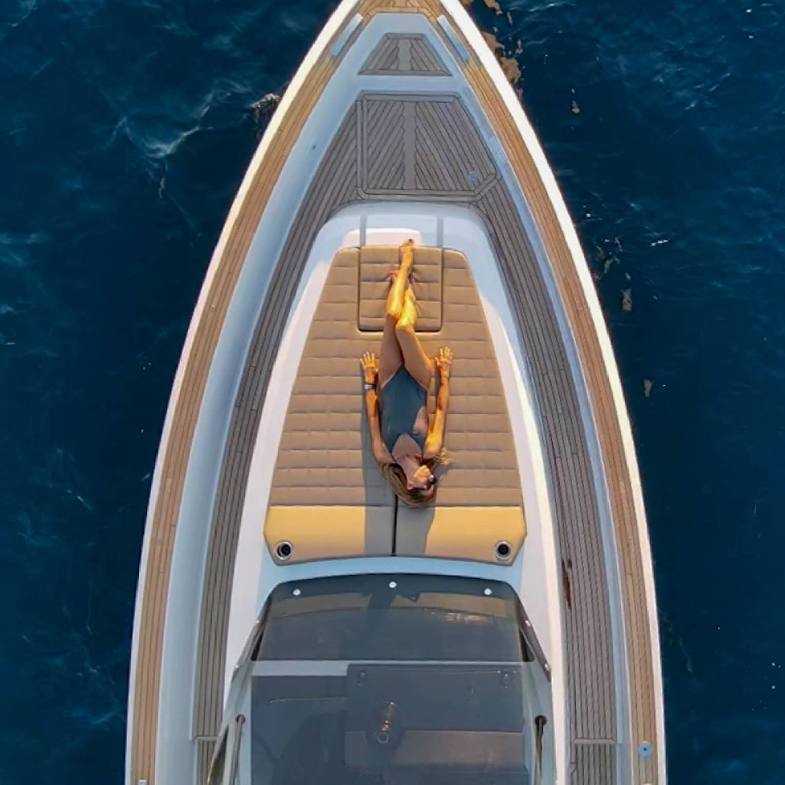 View from above of woman sunbathing on front deck of yacht.