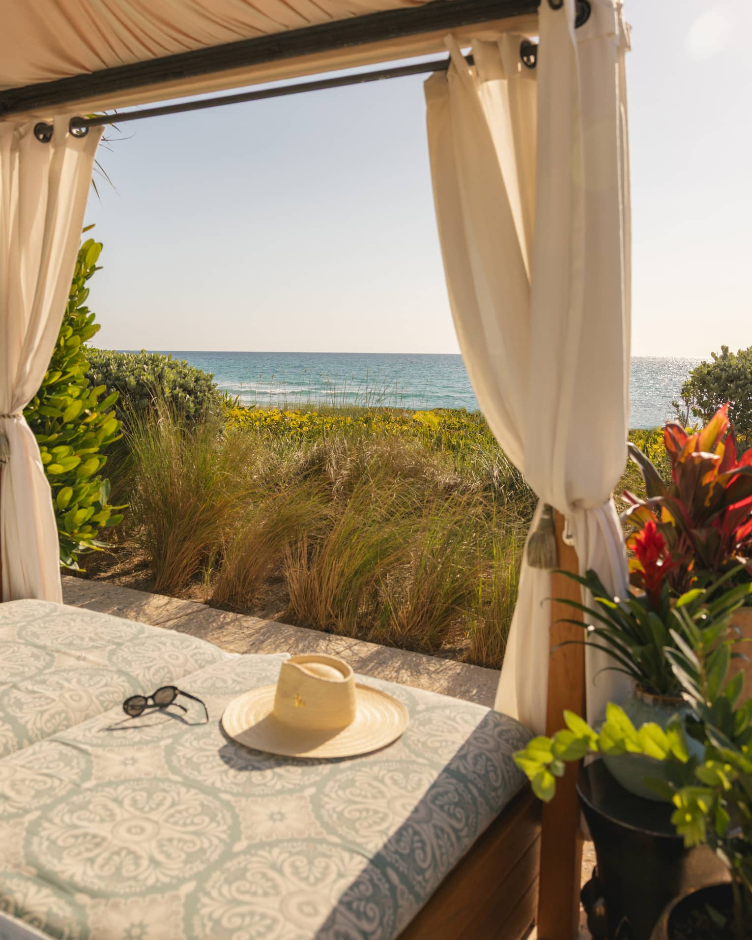Beachside cabana overlooking the ocean with a hat lying on the cushion