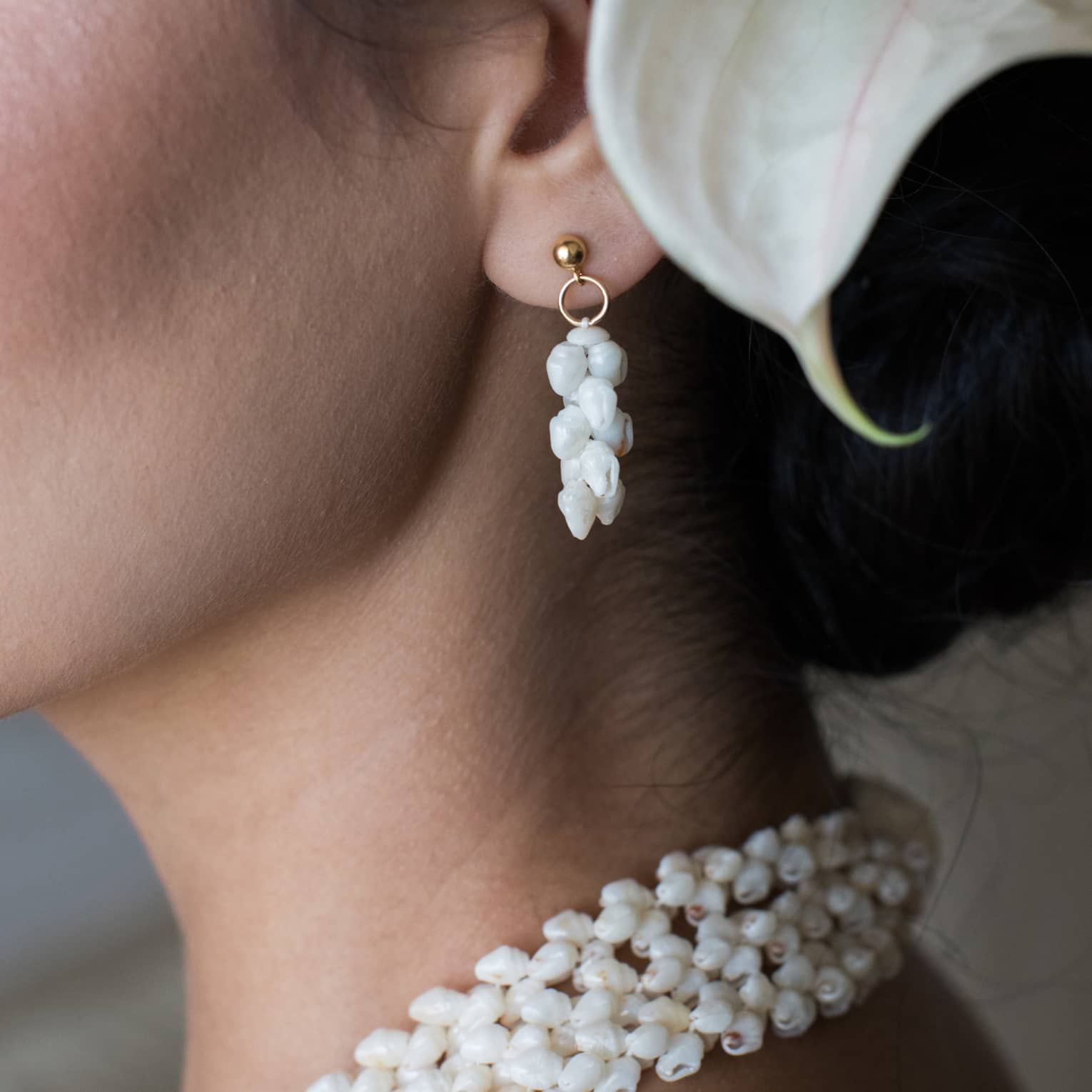A woman wears seashell-inspired earrings and matching necklace