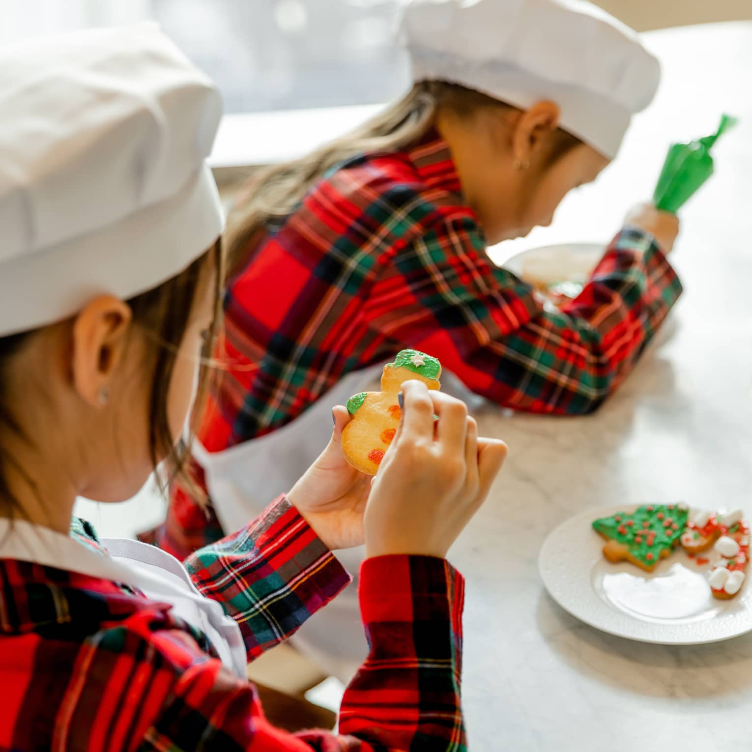 Two kids decorate holiday cookies