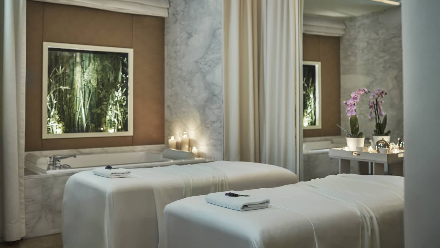 Spa couples massage beds with white sheets by candlelit tub