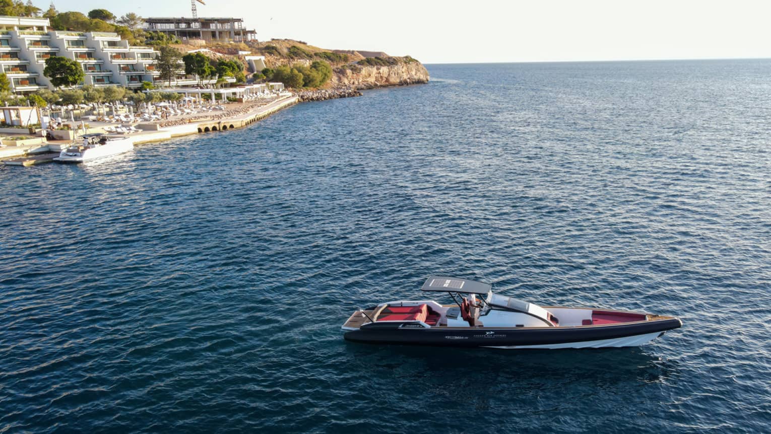 Small Greek-style yacht heading out toward open water from Astir Palace Hotel dock.