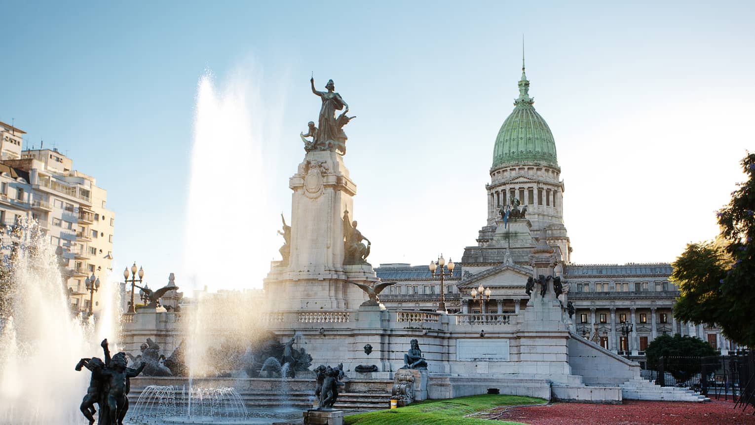 Large fountain, historic building and courtyard on sunny day