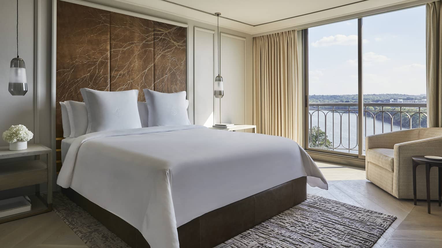 Governor's Suite hotel room bed under large leather headboard with branch pattern, large windows