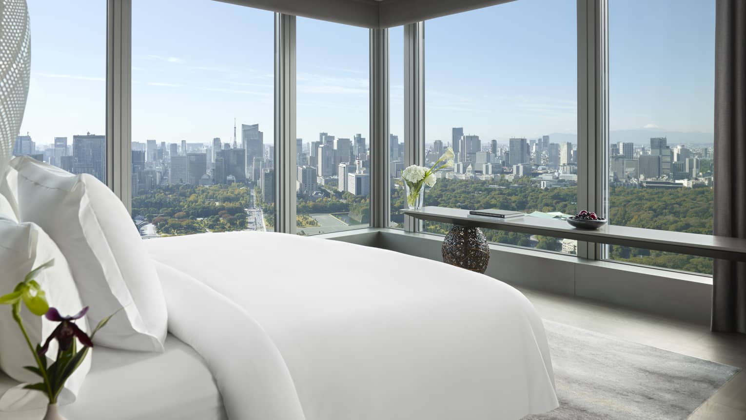 Panoramic hotel room with a king bed, side table with flowers and long console table with orchids