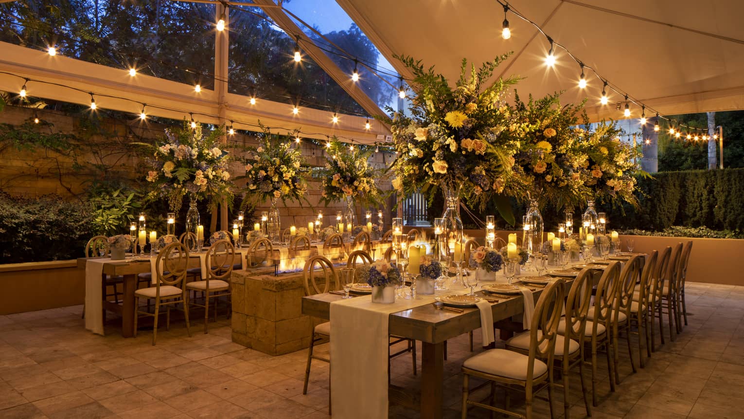Covered outdoor terrace with tables set for dinner at night