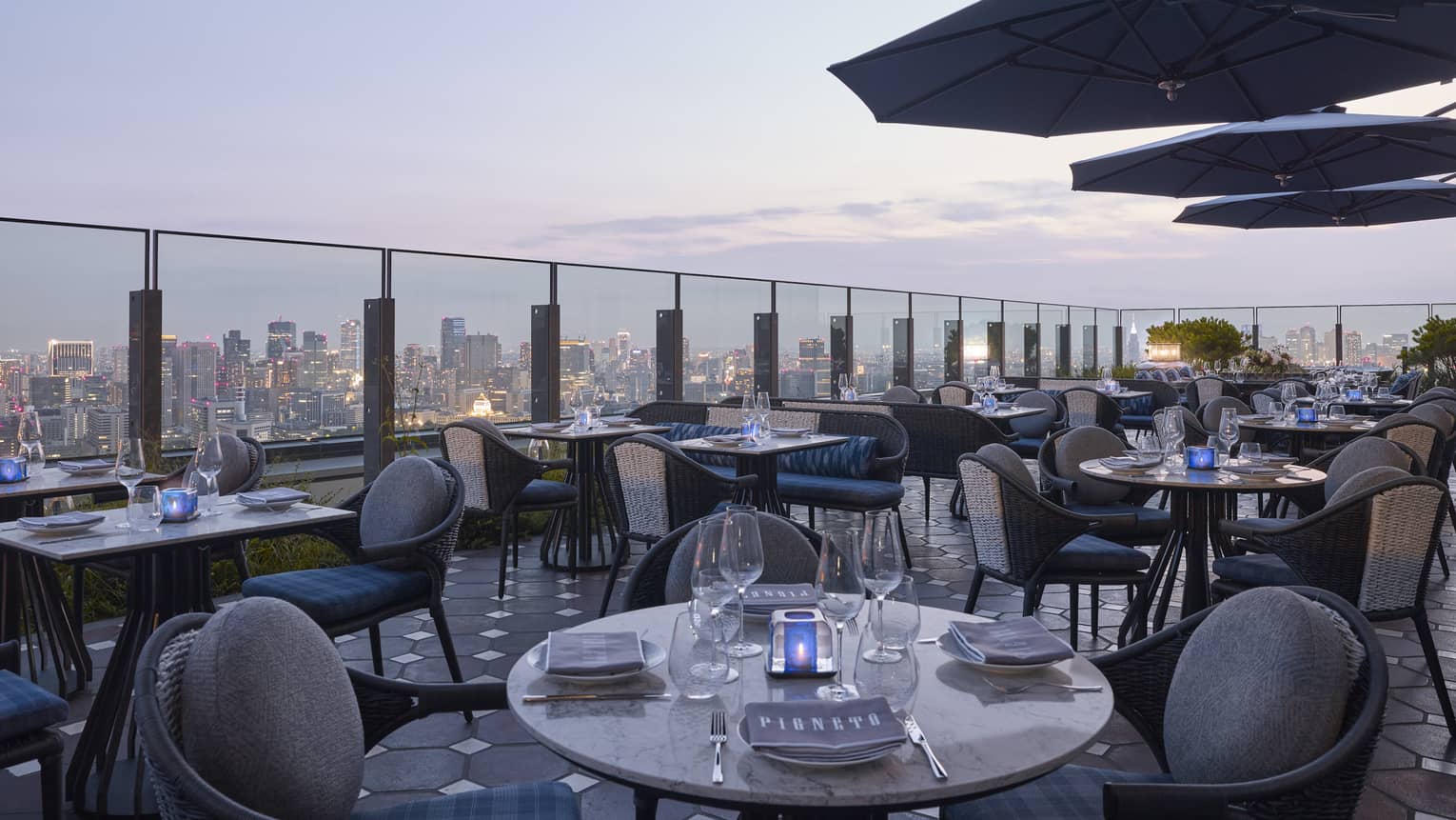 Pigneto Terraza rooftop patio dining tables at dusk, city view below