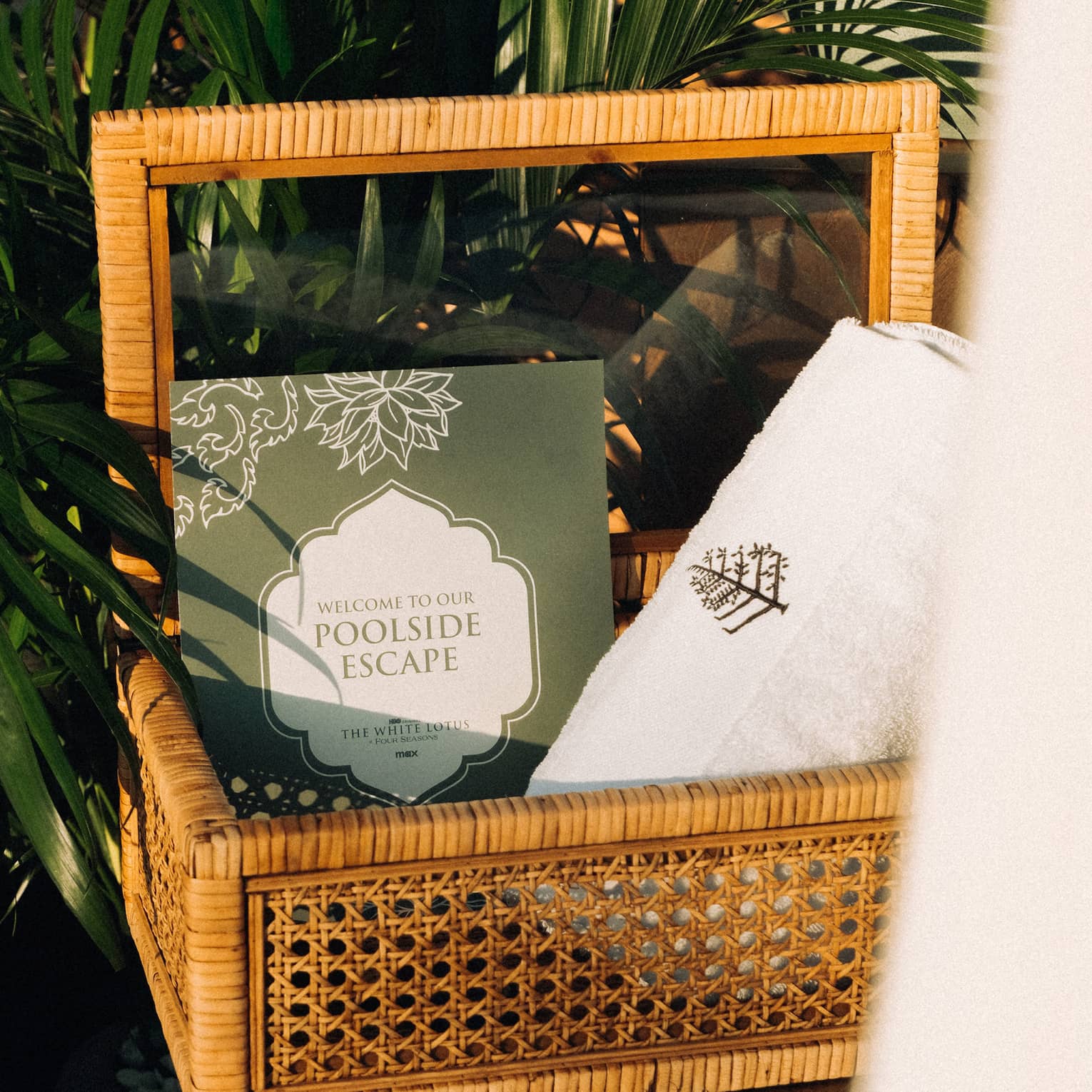 A basket beside a palm tree containing a Four Seasons towel