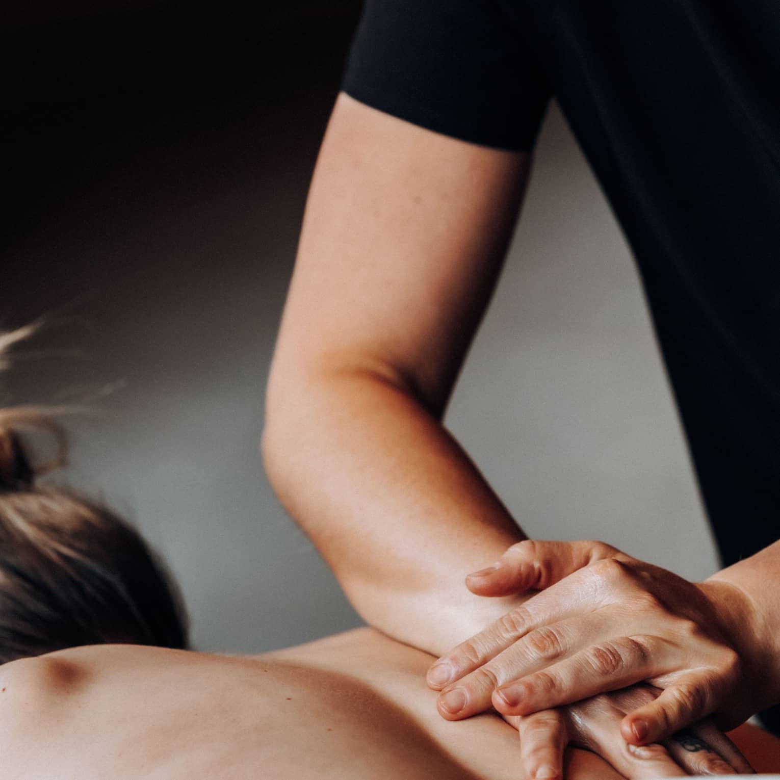 Massage therapists rubs a person's bare back with one hand placed on top of the other