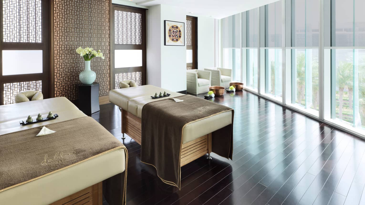 A couple's treatment room with floor-to-ceiling windows overlooking a garden. 