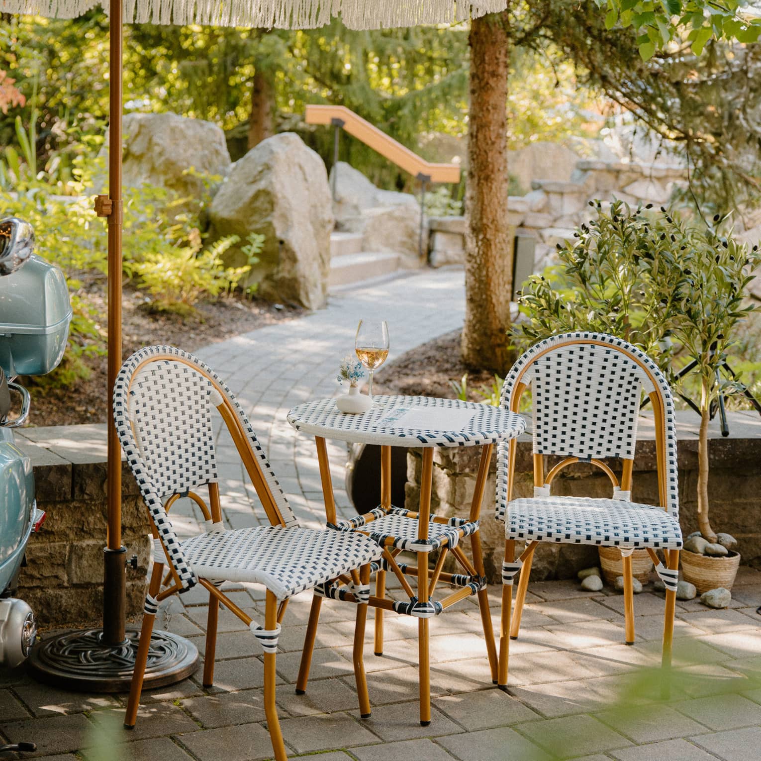 Two polka-dotted chairs and matching two-seater table on stone patio with walkway leading to steps