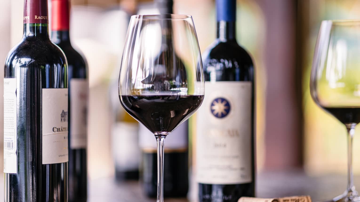 Closeup of glass of red wine, bottles beside it