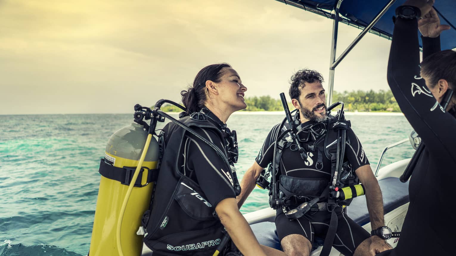 Three people in scuba gear on a boat. 