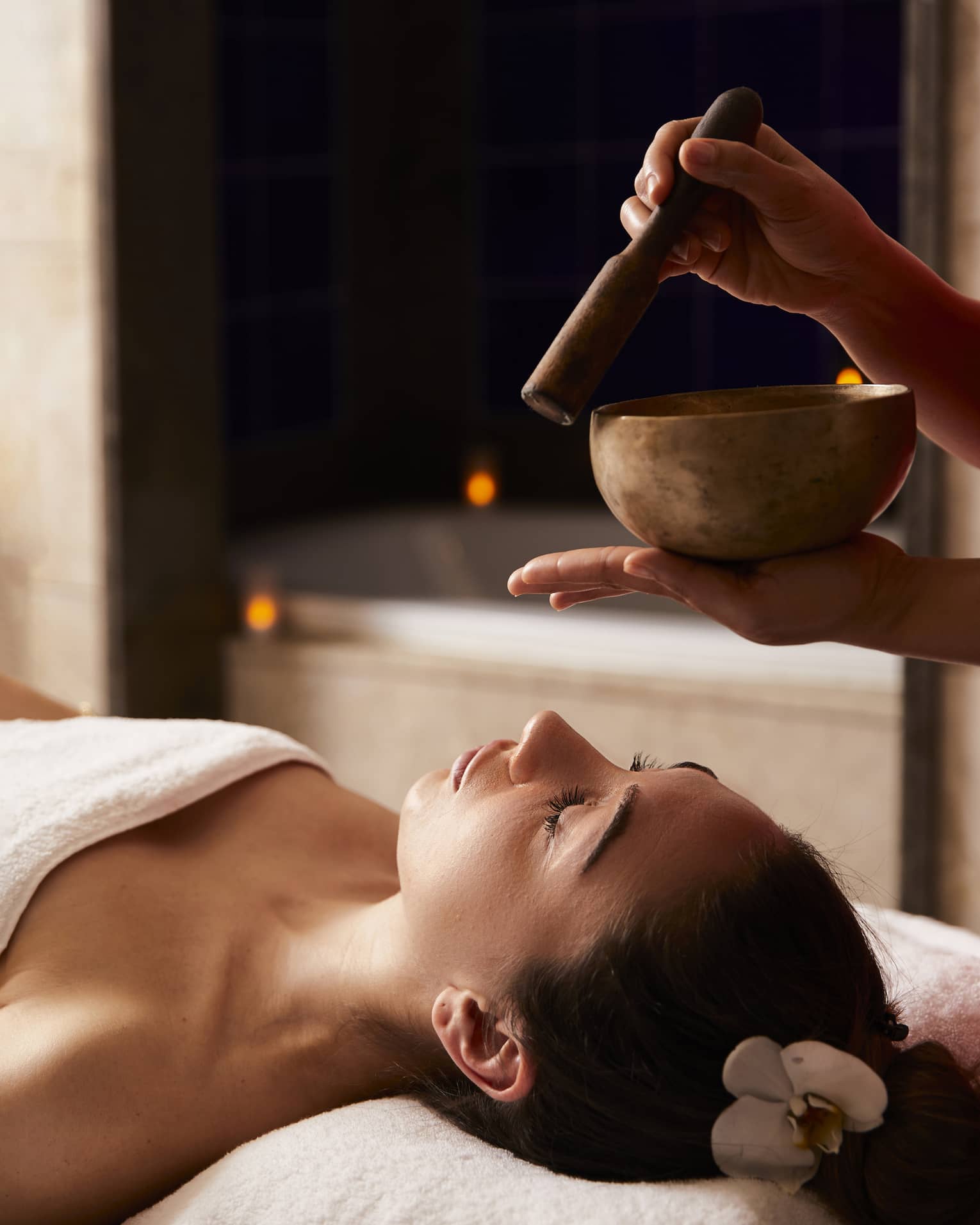 A woman receiving a spa treatment with bowls to create sounds.
