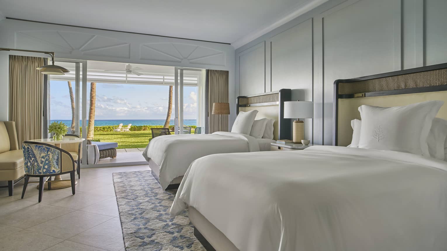 Hotel room with two double beds and walk-out terrace with tropical lawn/ocean view