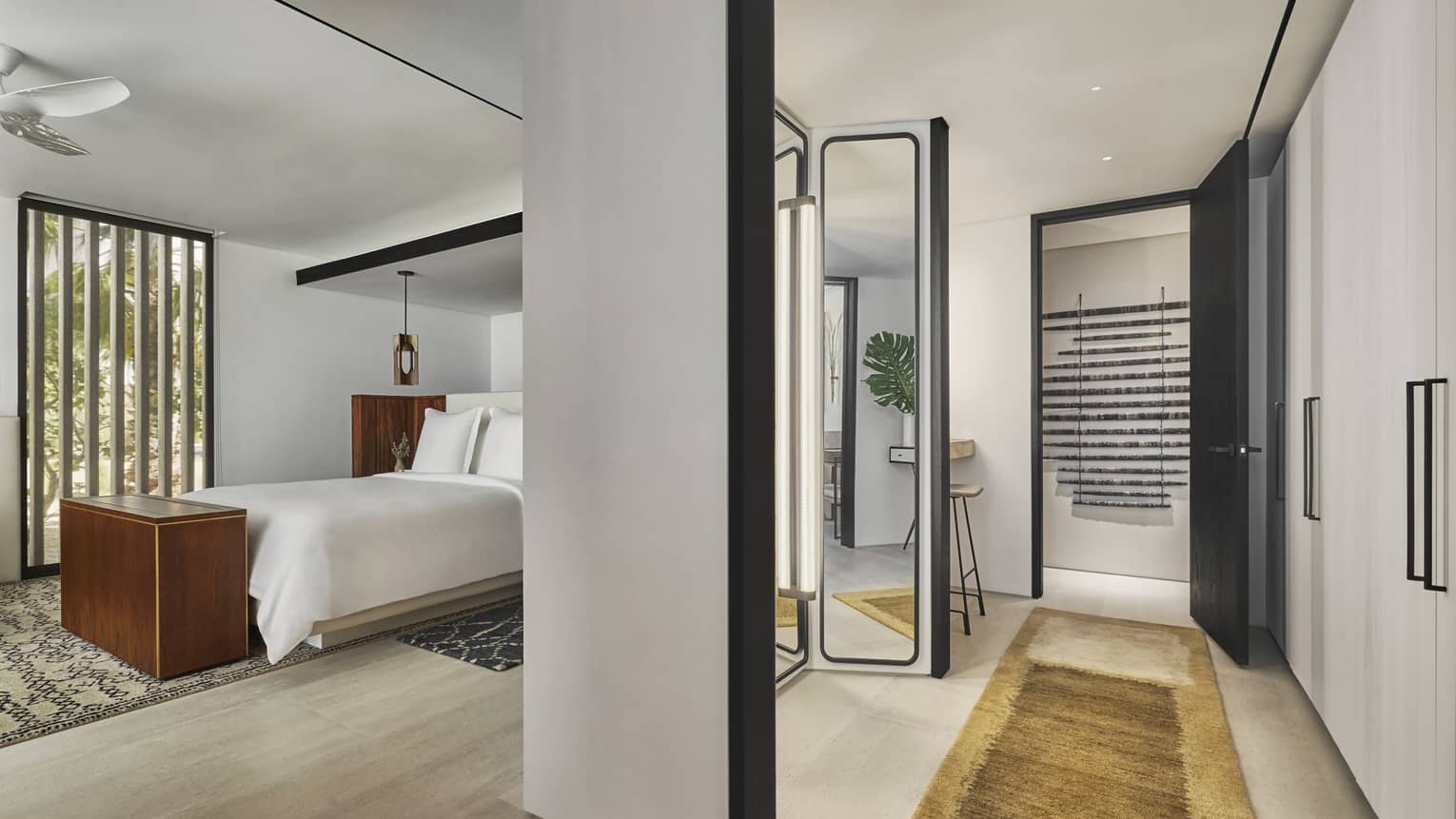 A suite with a bed, dresser, mirror and hall leading to a door.