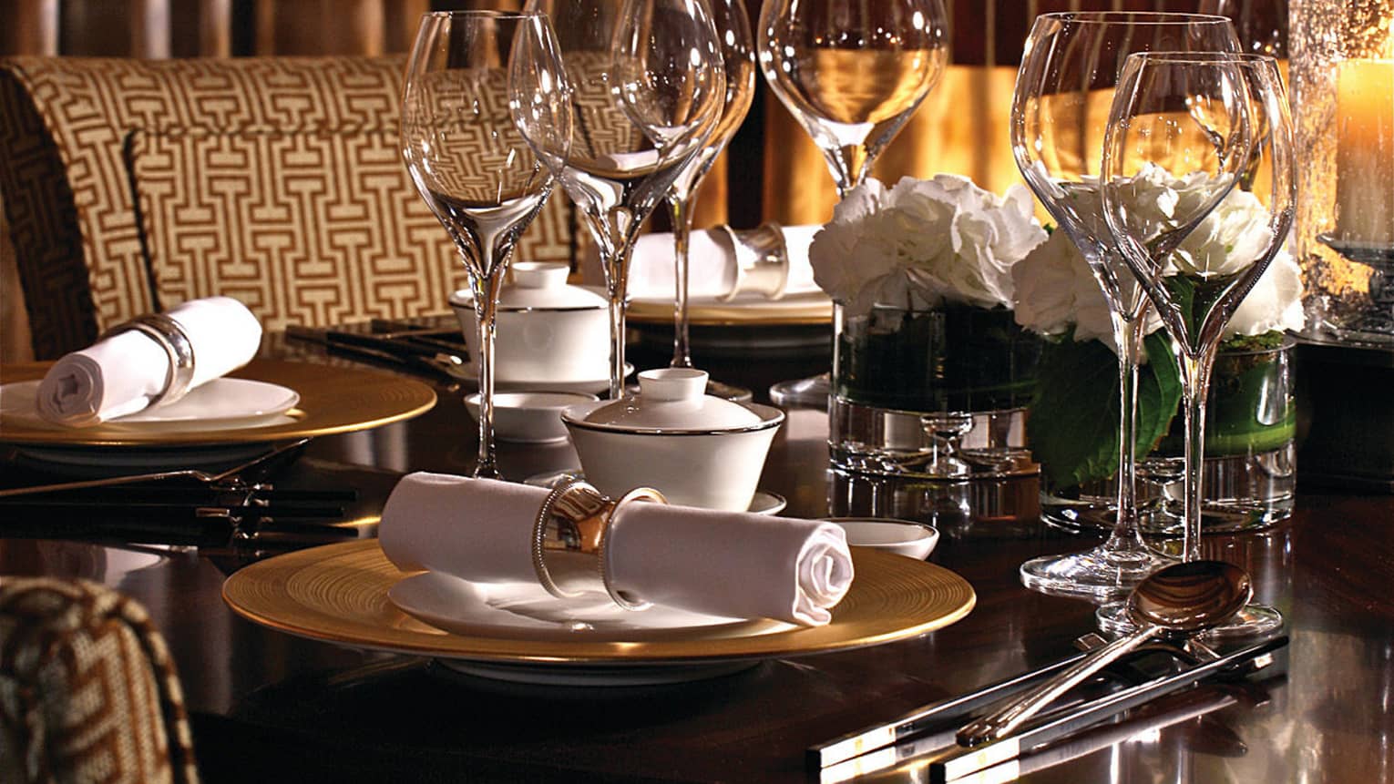 Close-up of dining table with empty wine glasses, place settings, cutlery rolled in white napkin