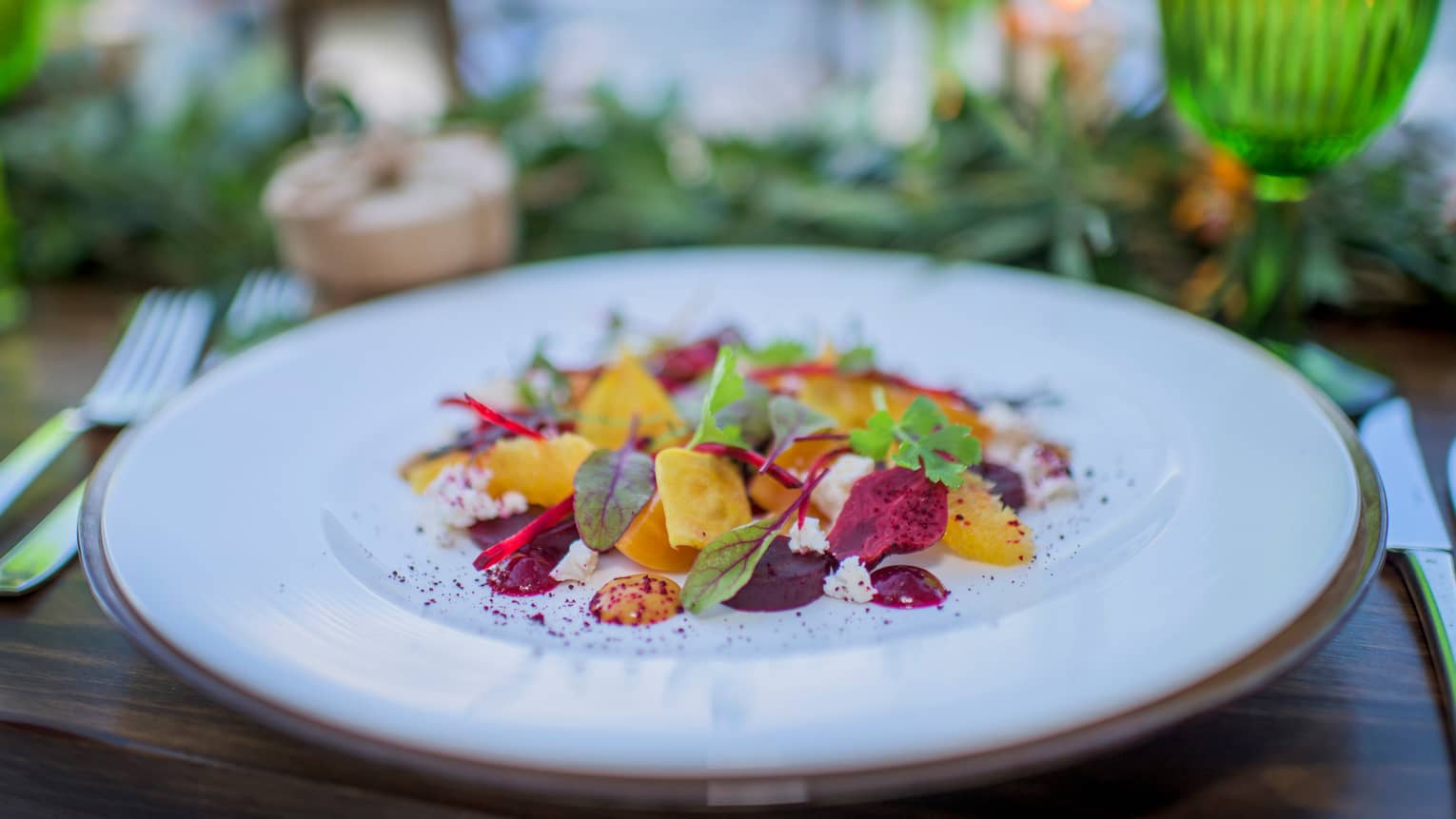 Close-up of fresh red and golden beet salad with goat cheese, greens on patio table