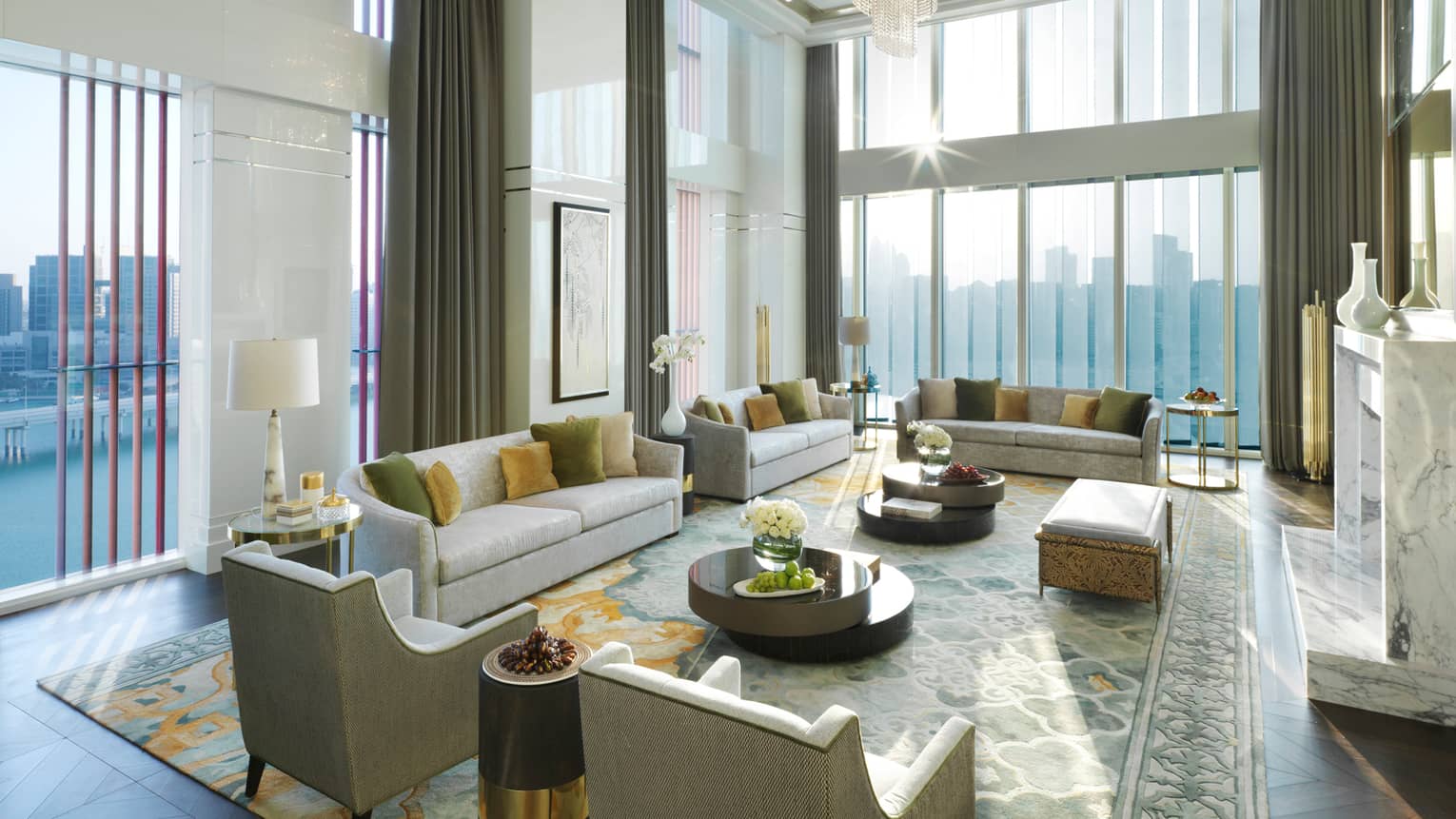 Royal Suite with high dome ceiling, modern crystal chandelier, sunny living room with several sofas and chairs, area rug