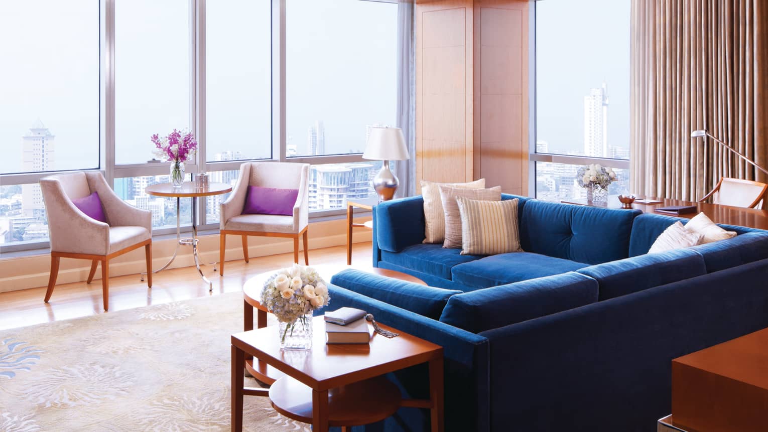 Deluxe Suite-Sea room with blue sectional sofa by floor-to-ceiling sunny windows, chairs
