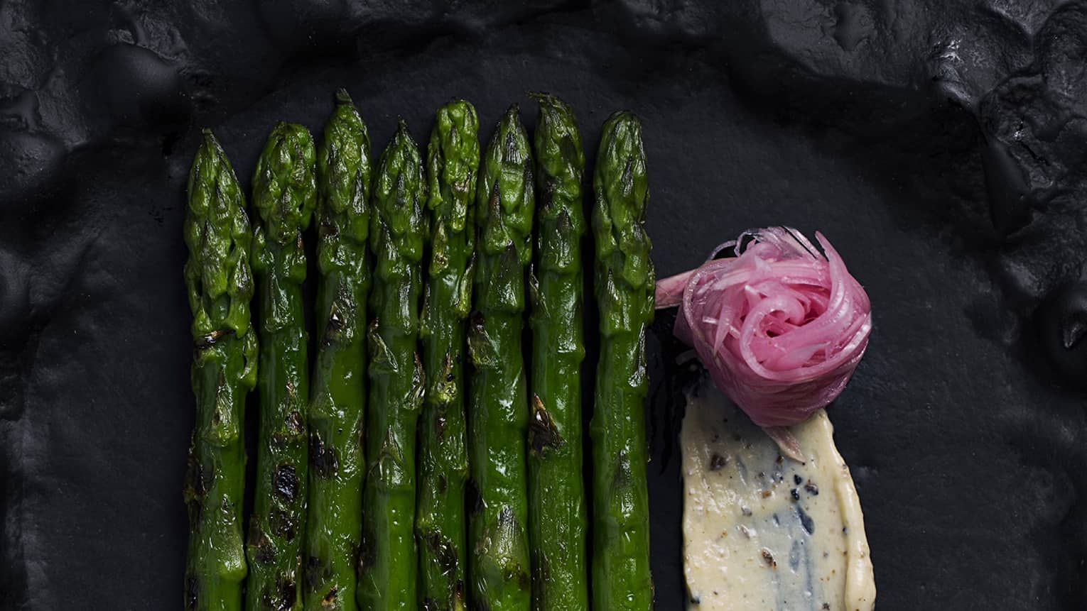 Grilled green asparagus on a black plate