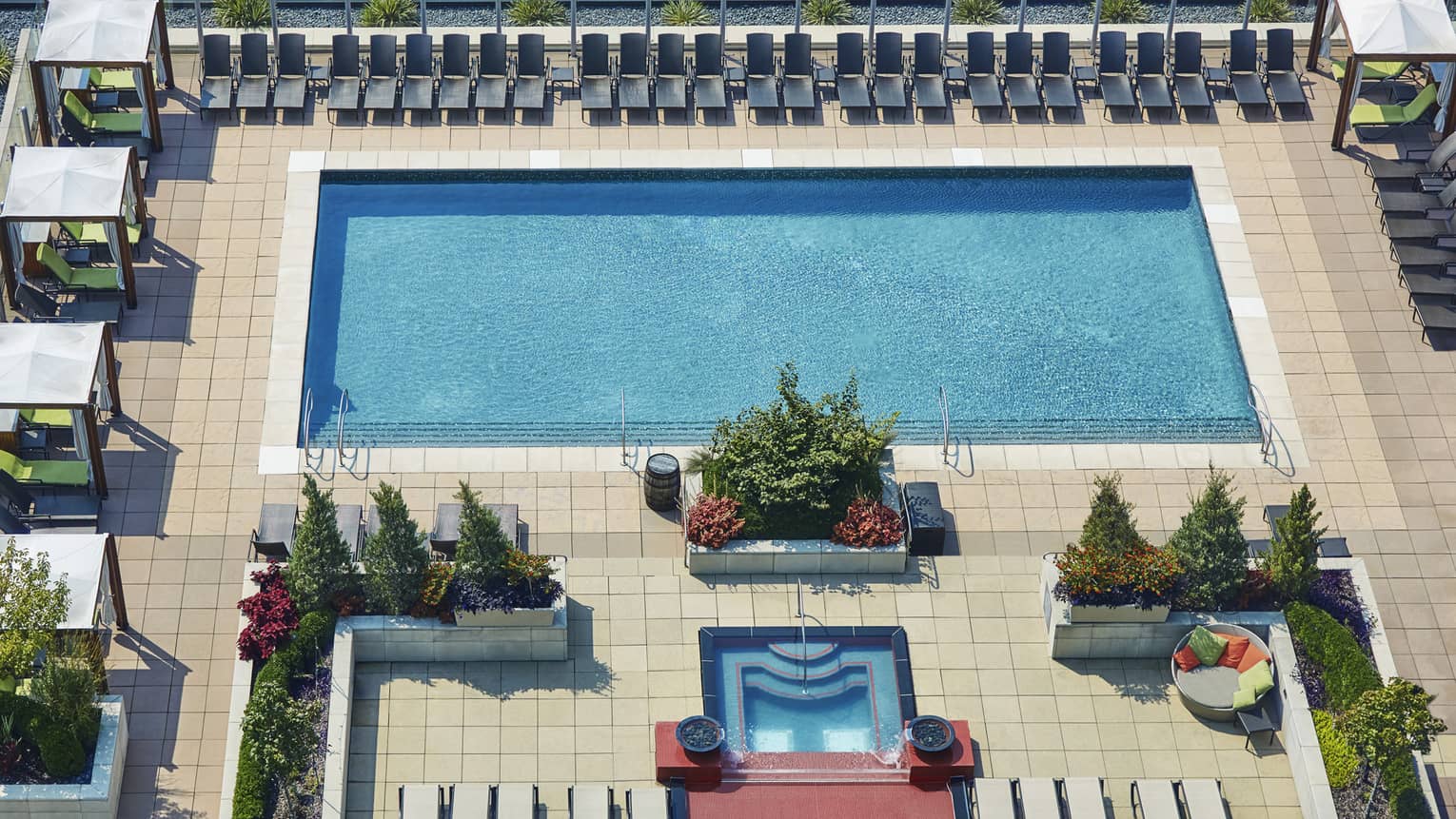 Aerial view of rooftop outdoor swimming pool and rows of patio chairs, cabanas
