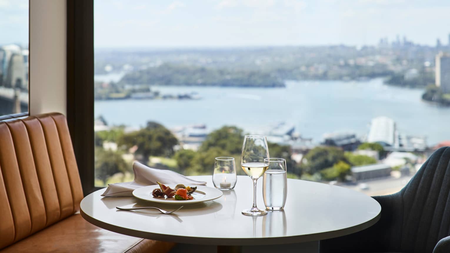 Lounge 32 meal, glass of white wine on round table by window with harbour views