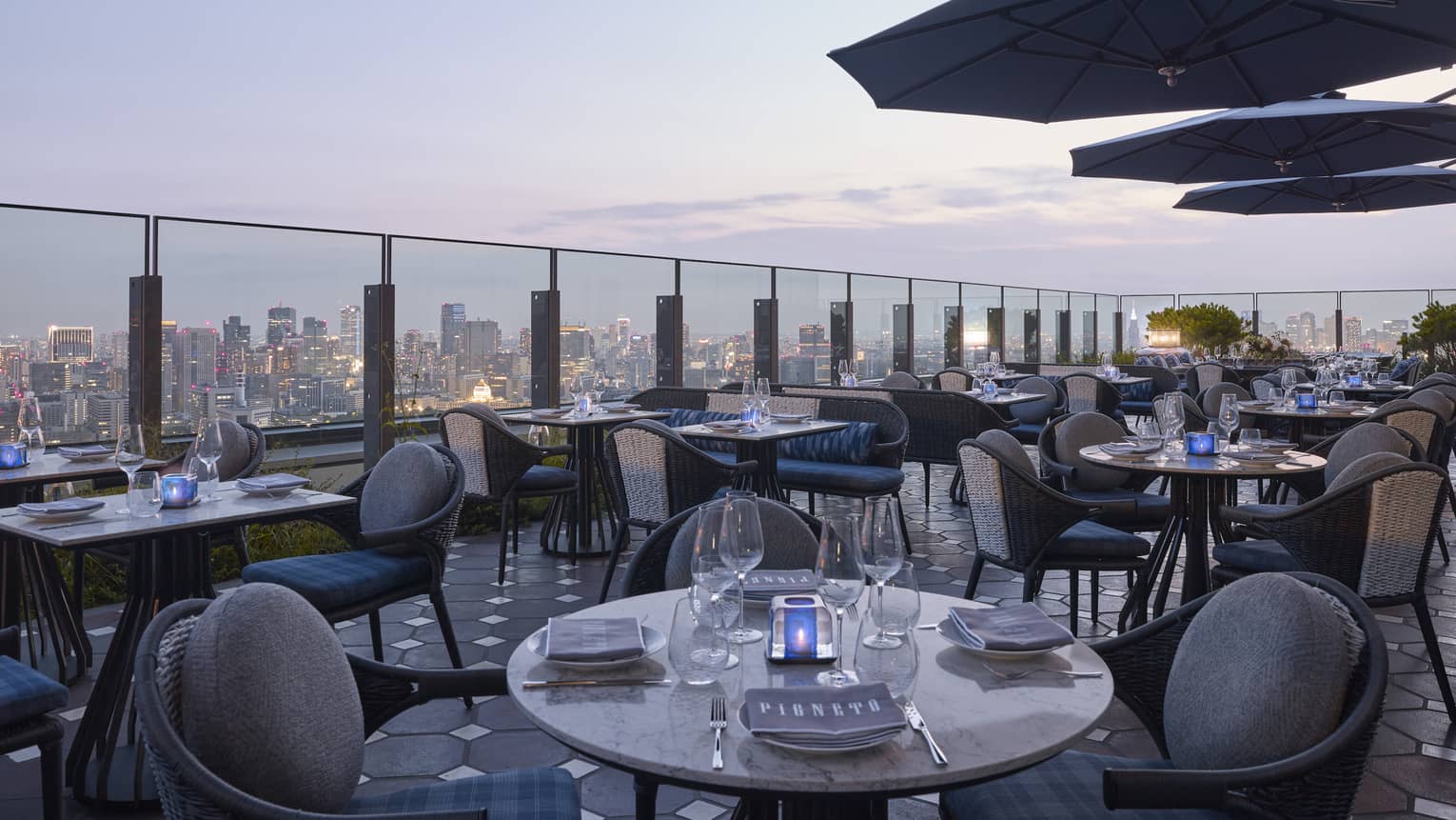 Pigneto Terraza rooftop patio dining tables at dusk, city view below