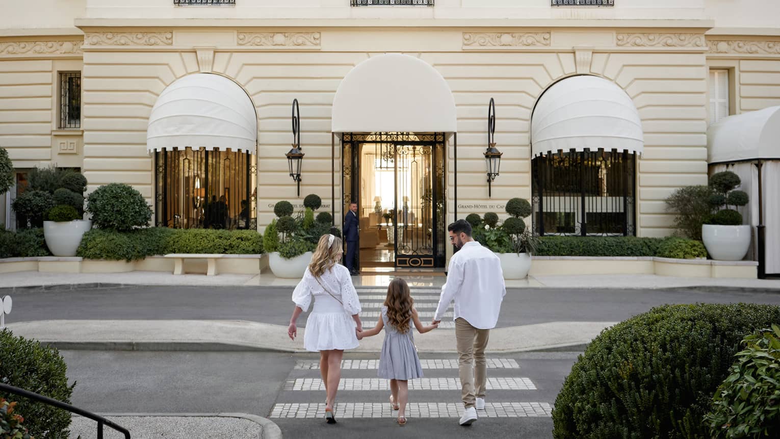Family of three holding hands while walking toward the Grand-H�tel