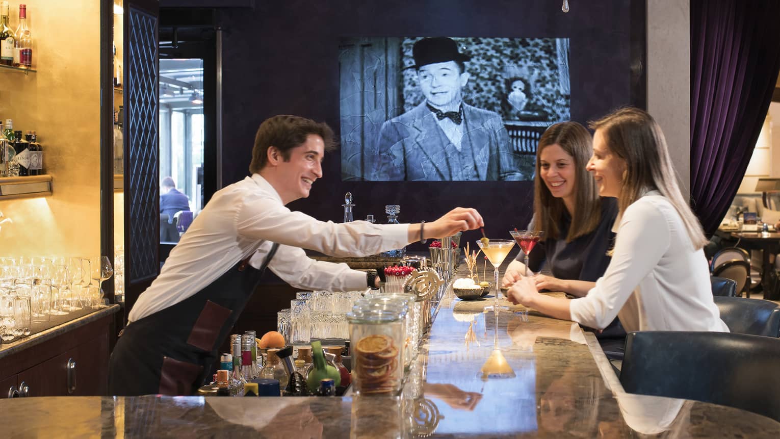 Bar and lounge at luxury hotel with two women drinking and a bartender serving cocktails