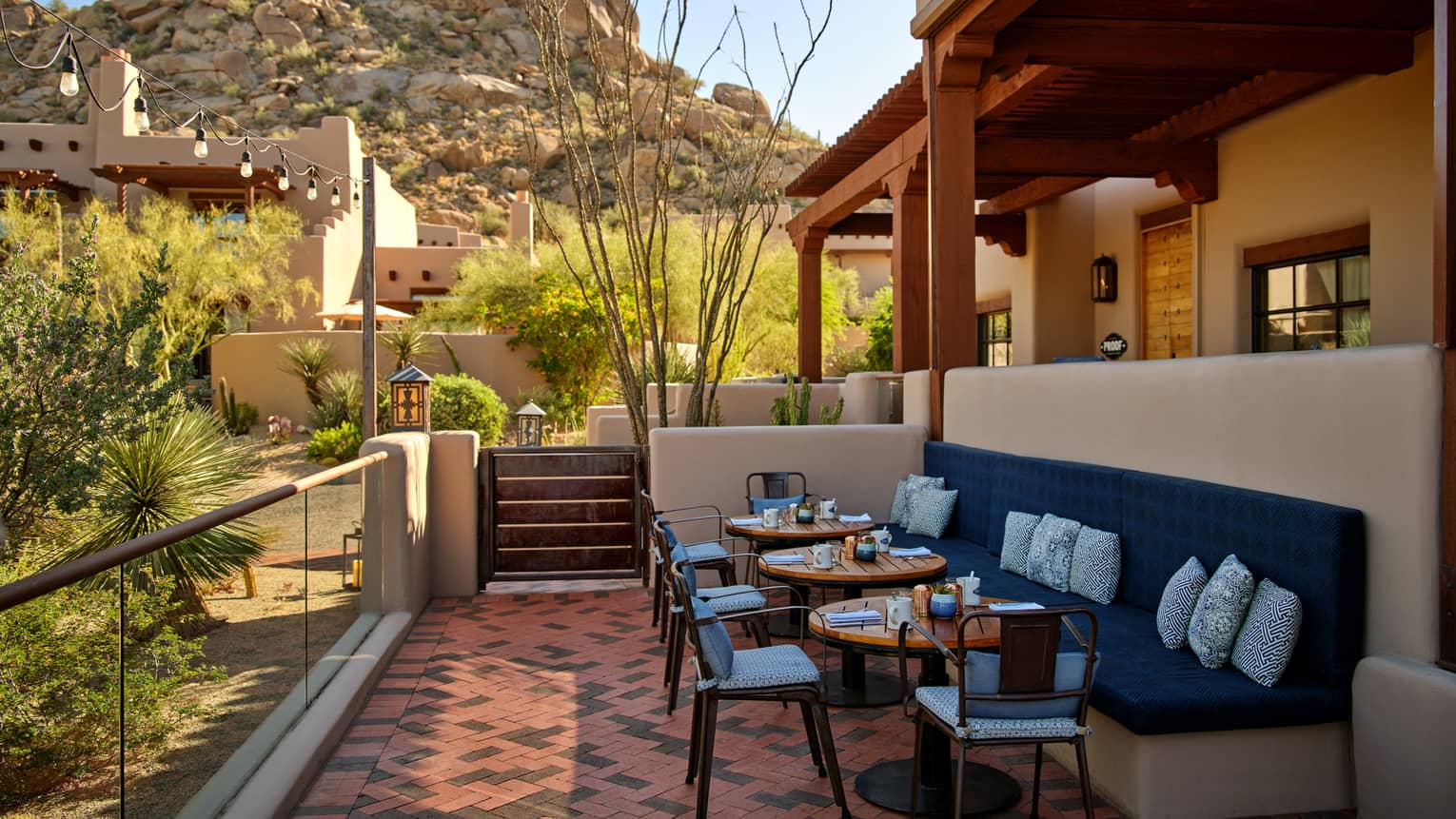 Outdoor terrace with booth seating and chairs and a view of the mountains.