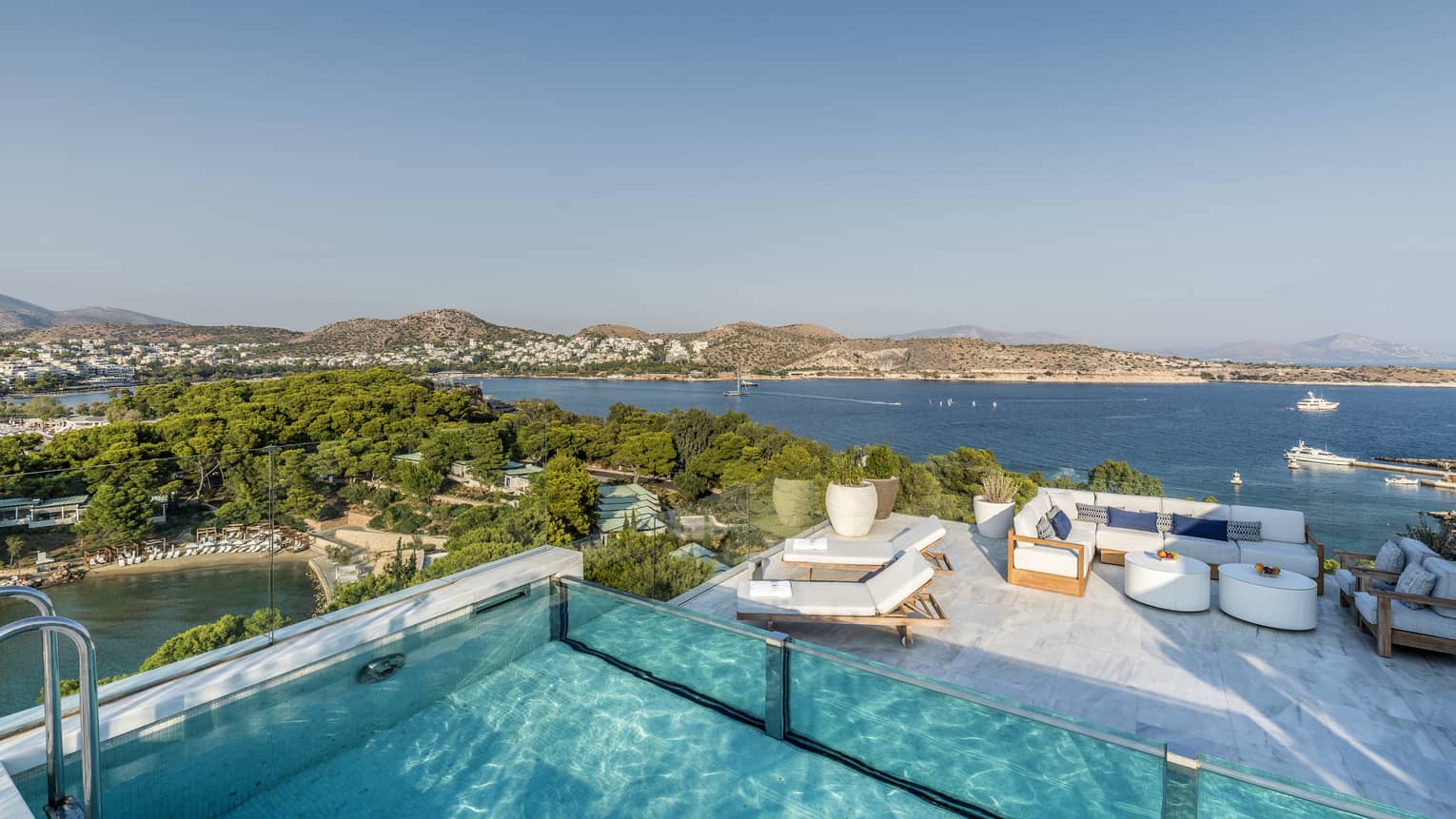 Arion Riviera Suite Rooftop with plunge pool, lounge area below with white sofa and dining table, view of the Mediterranean Sea