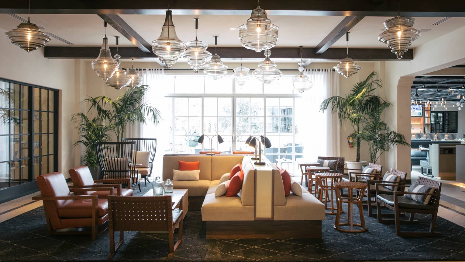 Seasons Restaurant lounge with L-shaped white sofas, armchairs and cocktail tables under modern glass chandelier display 