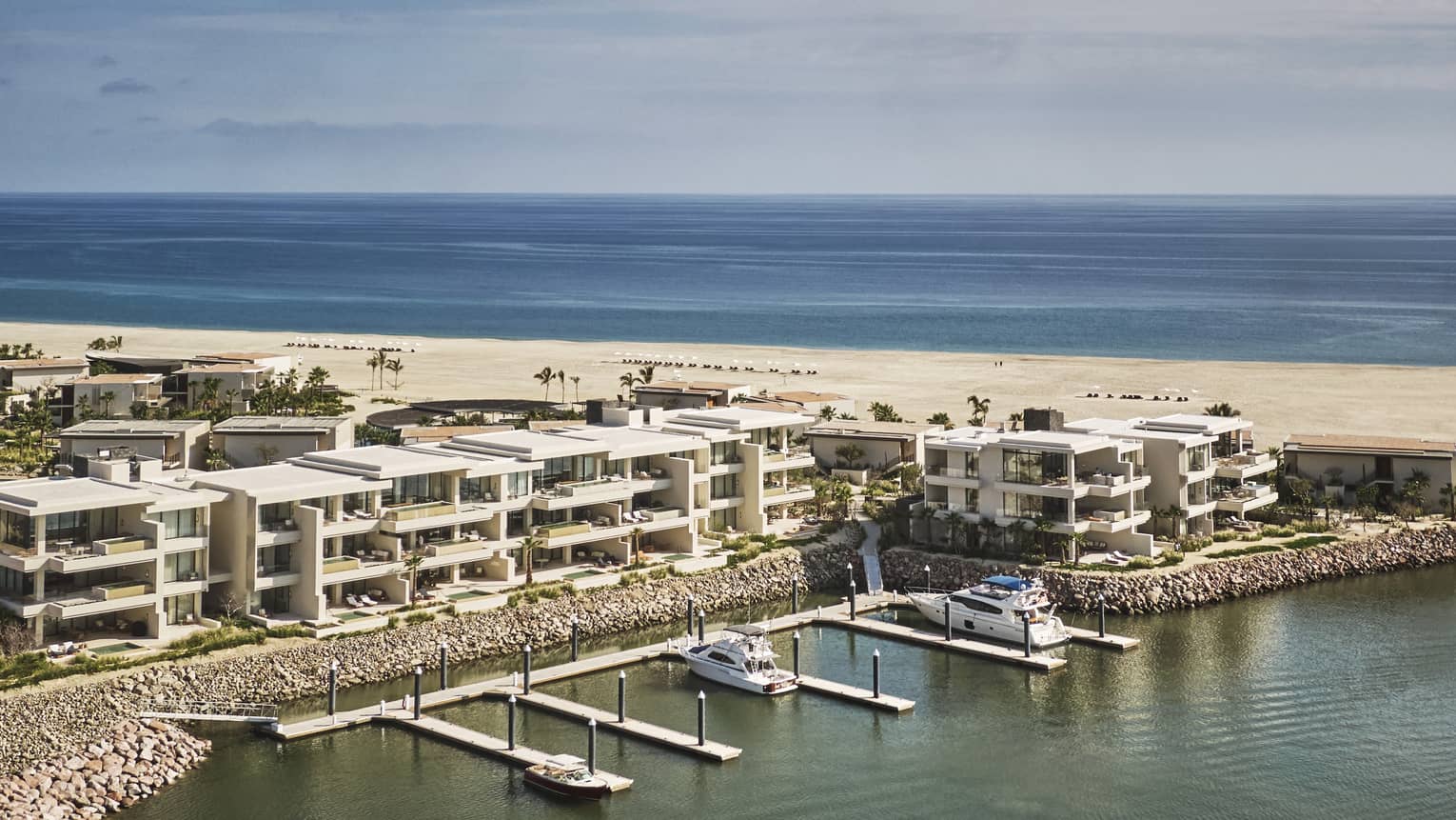 View of villas along a marina with the ocean in the background