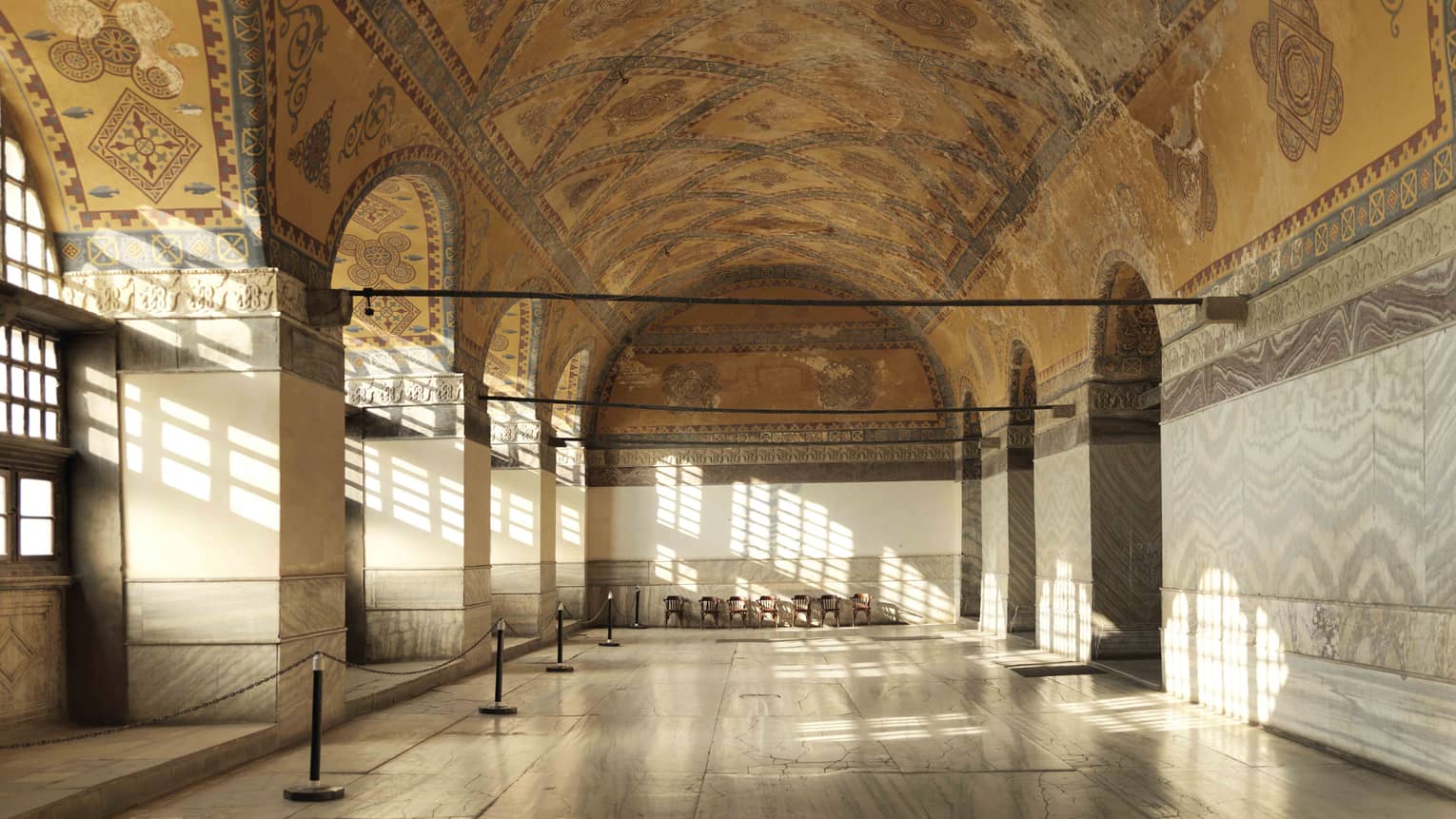 Sun streams through windows into Hagia Sophia Museum with painted cathedral ceilings
