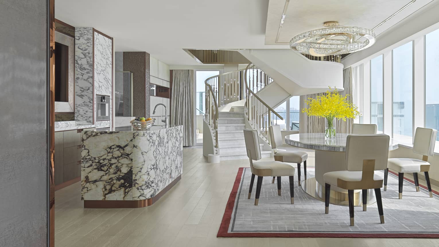 Skyview Villa with dining table and cream chairs, marble kitchen island, winding staircase, floor-to-ceiling windows, natural light