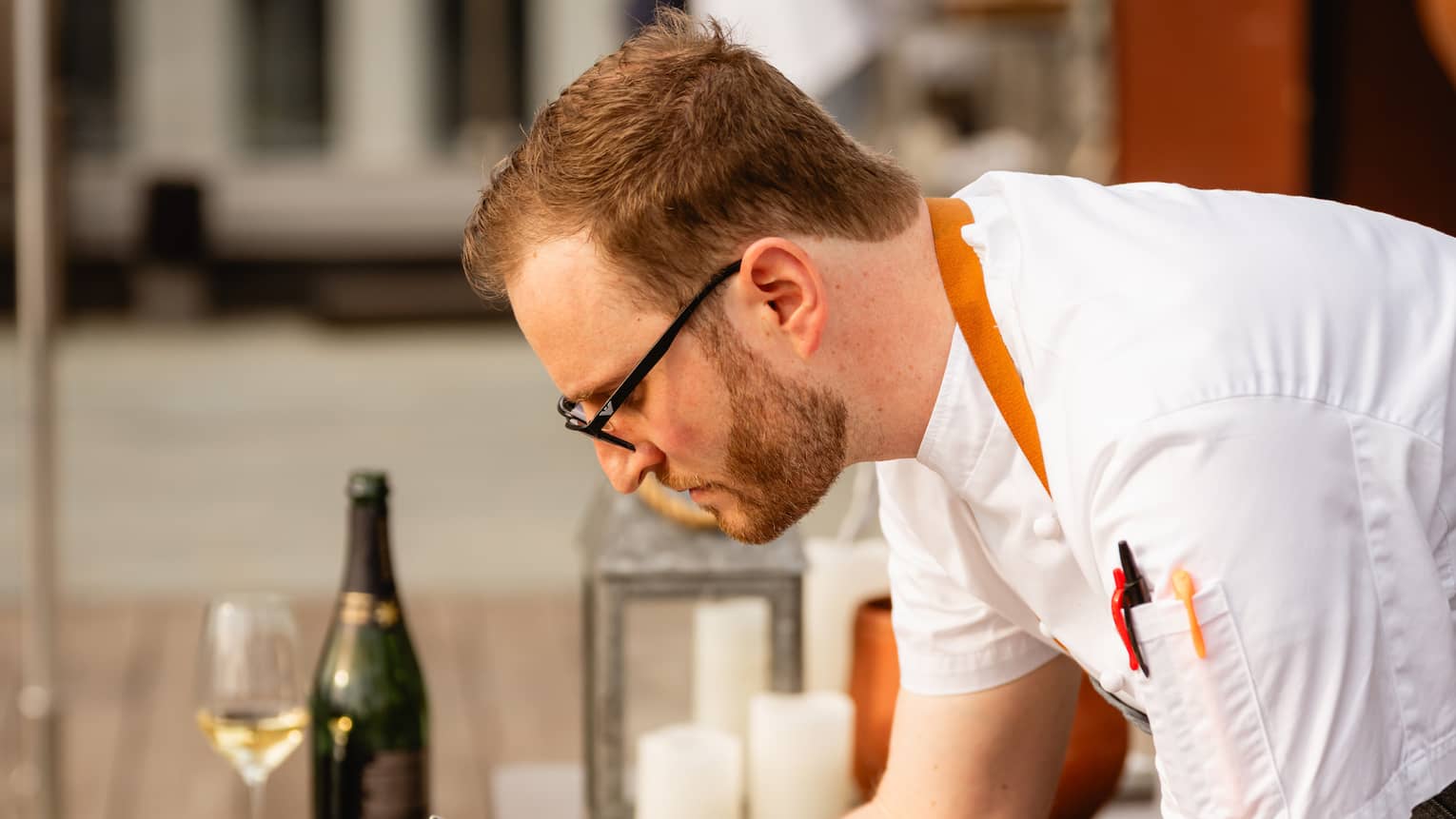 A chef putting toppings on a display of food on a dining table
