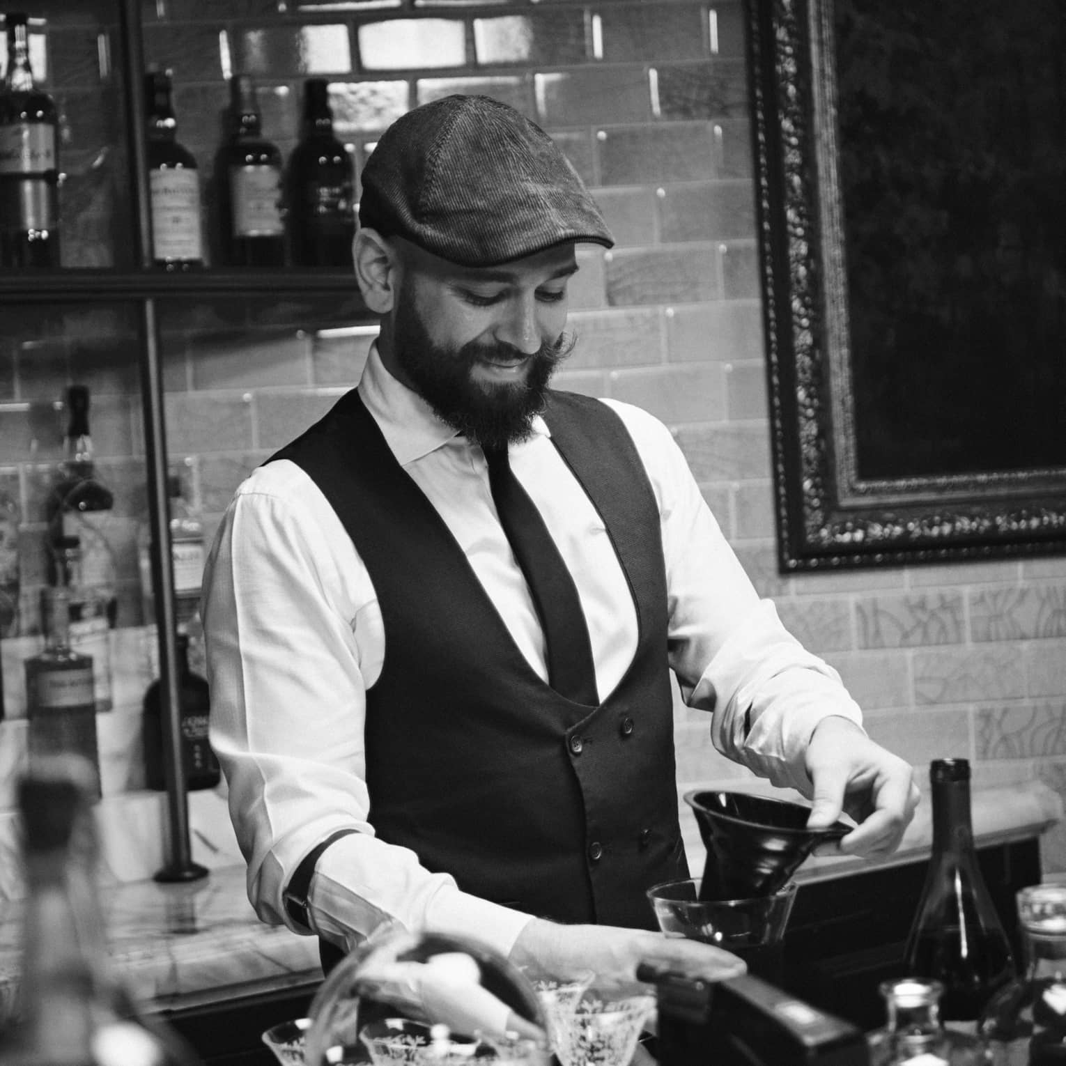 A bartender wearing a tie and vest works behind a bar