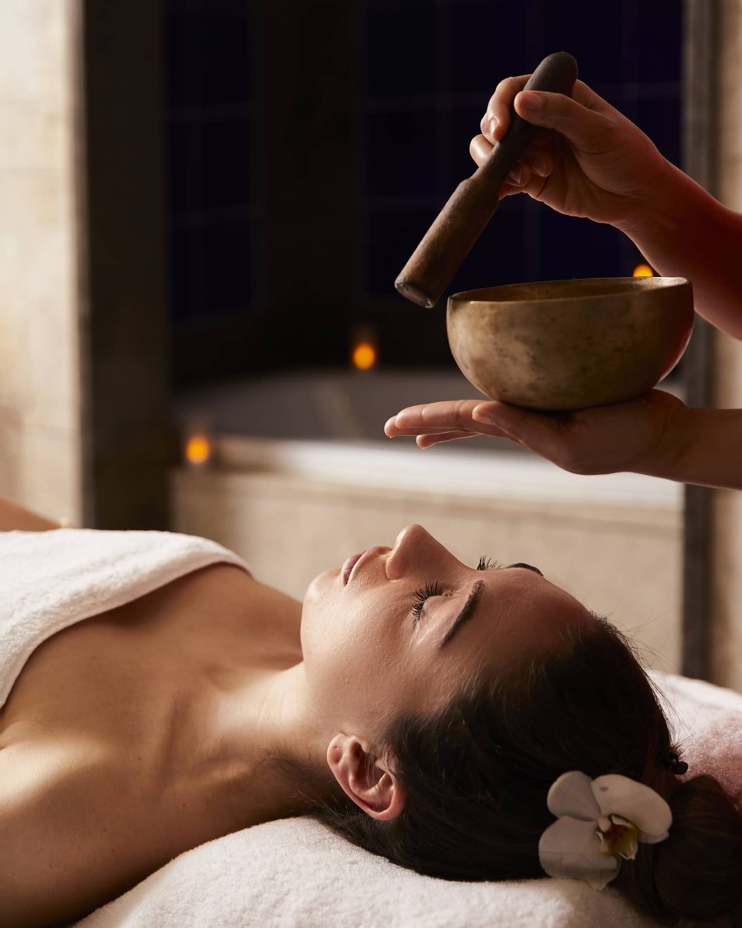 A woman receiving a spa treatment with bowls to create sounds.