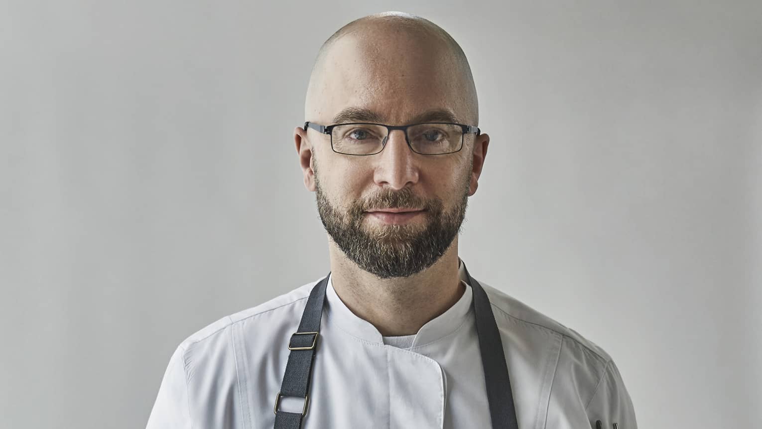 Chef wearing uniform holds copper pot with lobsters, potatoes