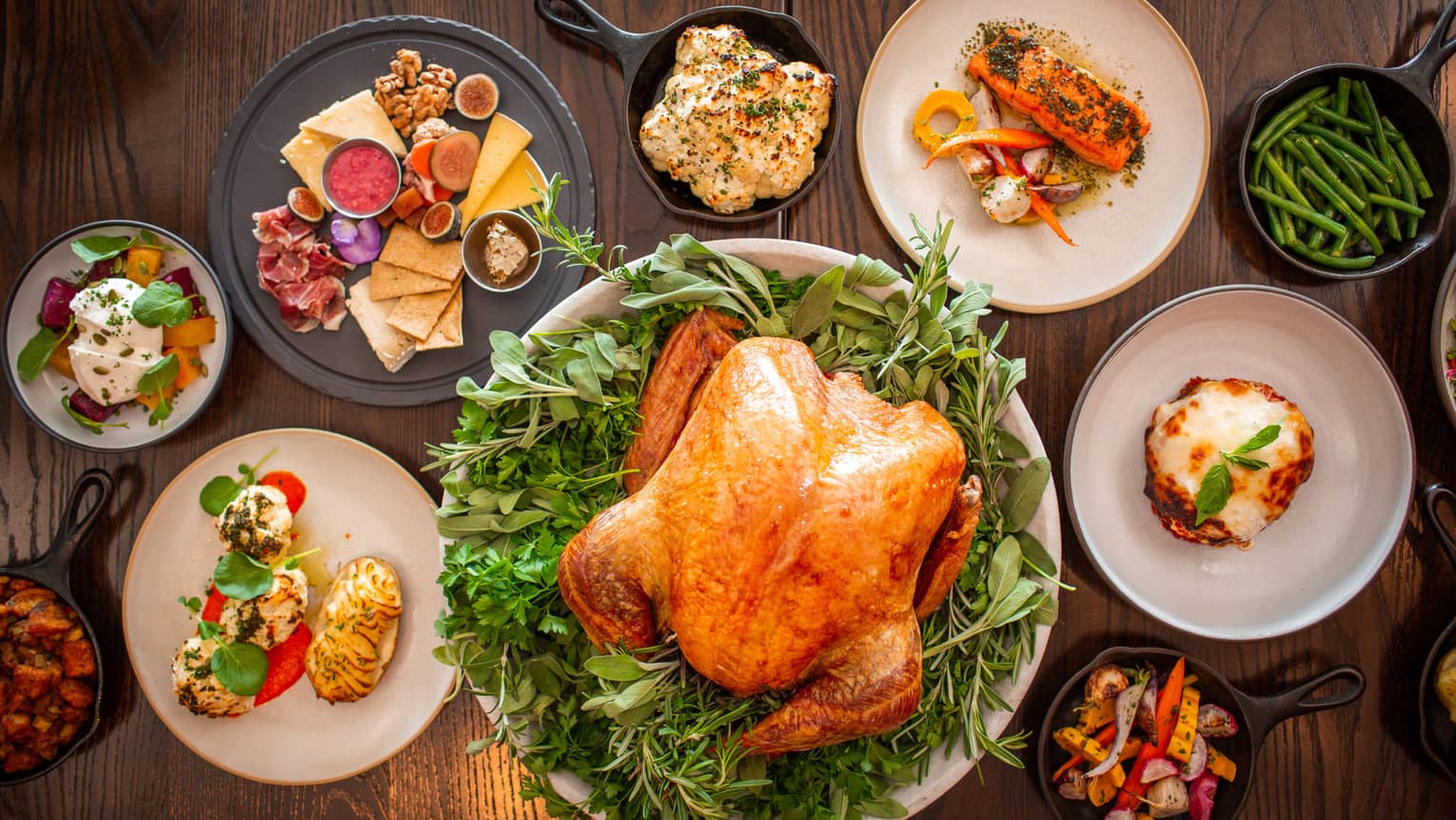 An assortment of thanksgiving food including Turkey, charcuterie, vegetables, and more.
