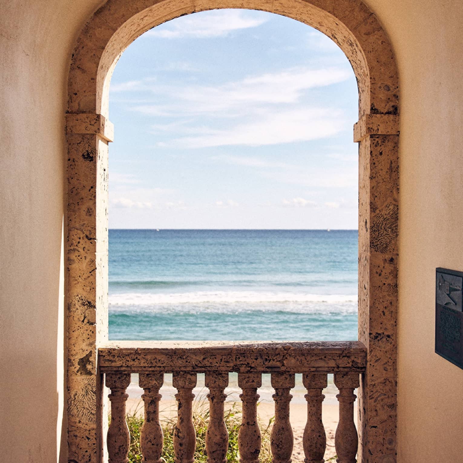 Arched doorway with a view of the shore, ocean and blue sky.
