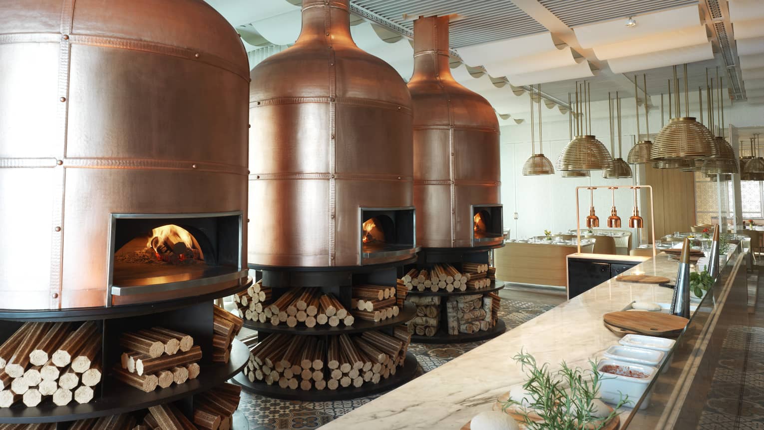 Three large fire burning pizza ovens behind a bar