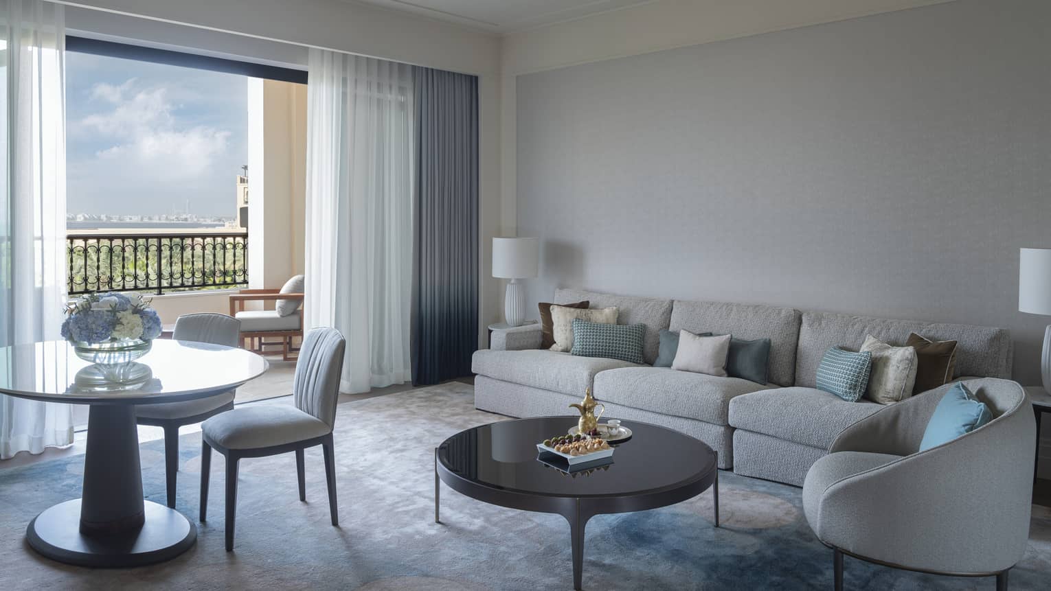 Hotel suite living room with sofa, arm chair, round table and two chairs, and a walk-out terrace