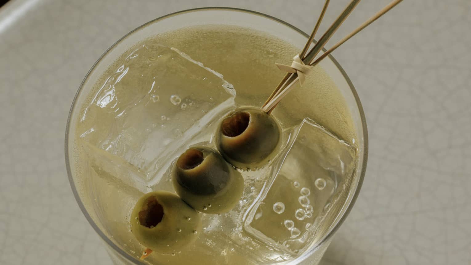 Gin-based cocktail garnished with three green olives