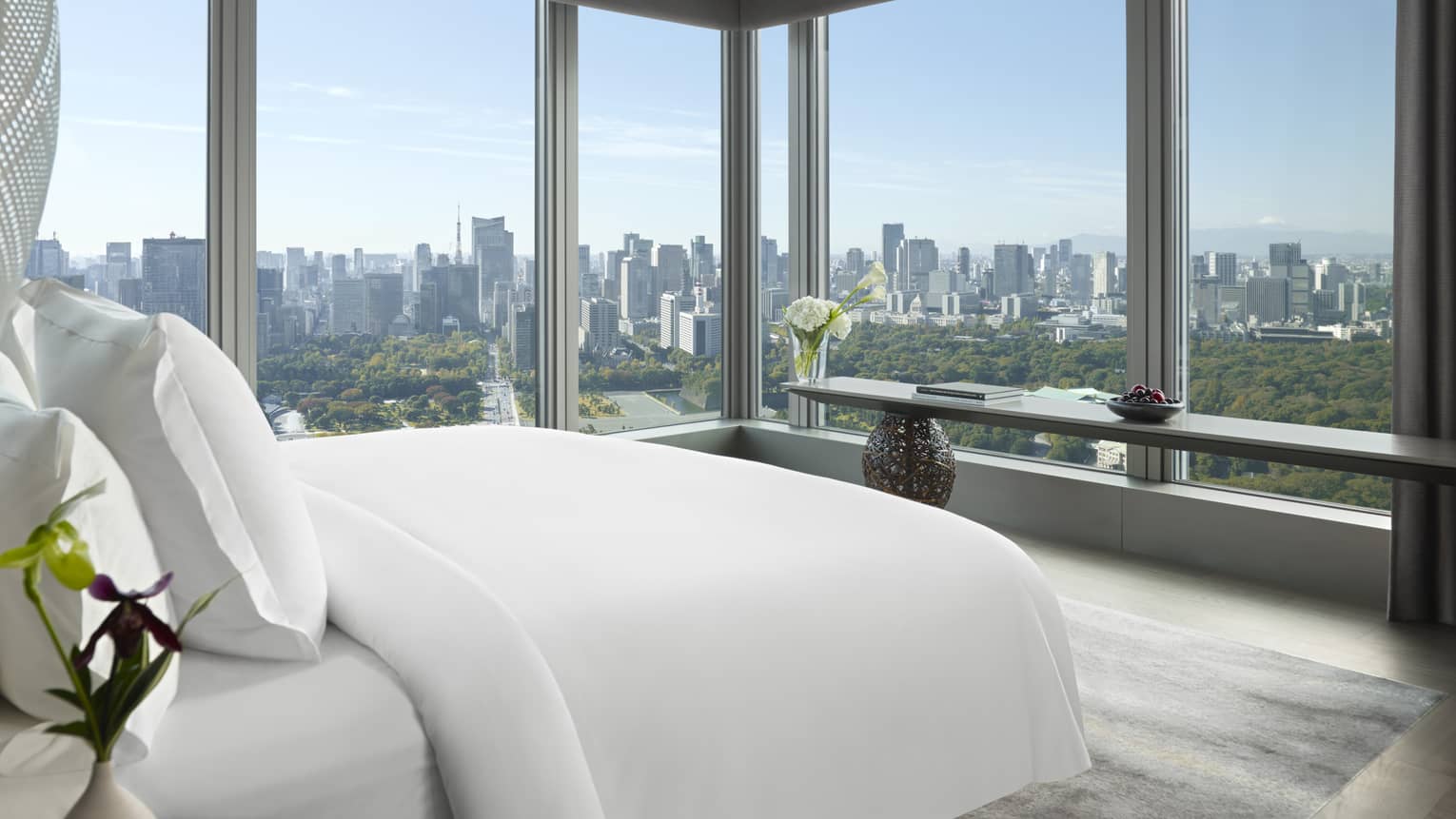 Panoramic hotel room with a king bed, side table with flowers and long console table with orchids
