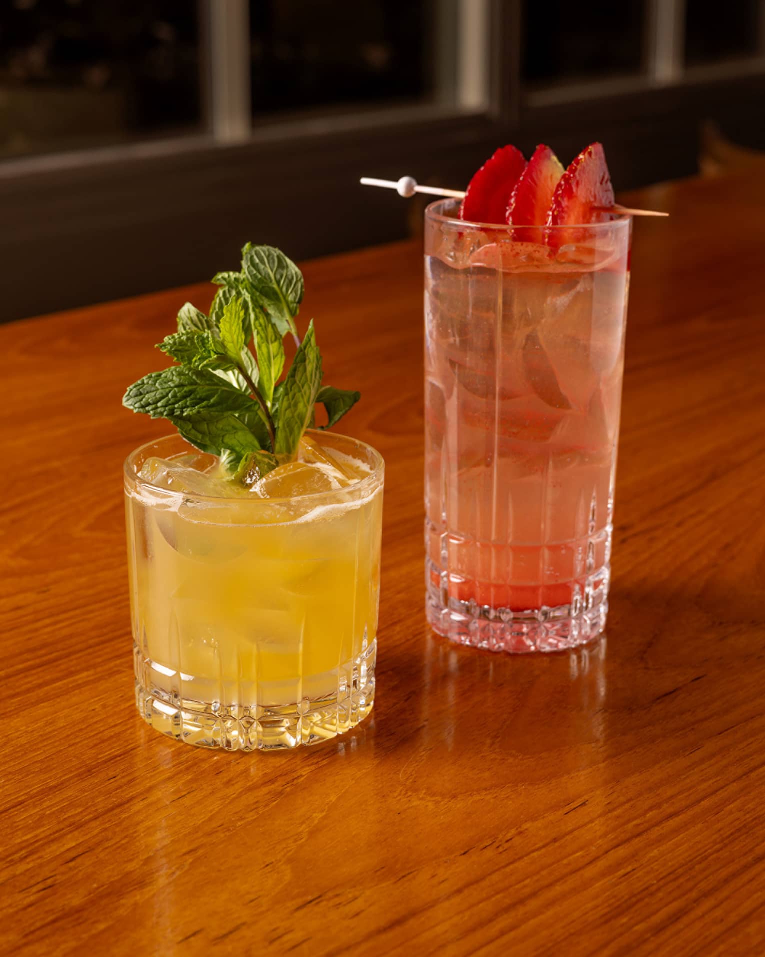 One yellow drink and one red drink placed beside each other on a dining table