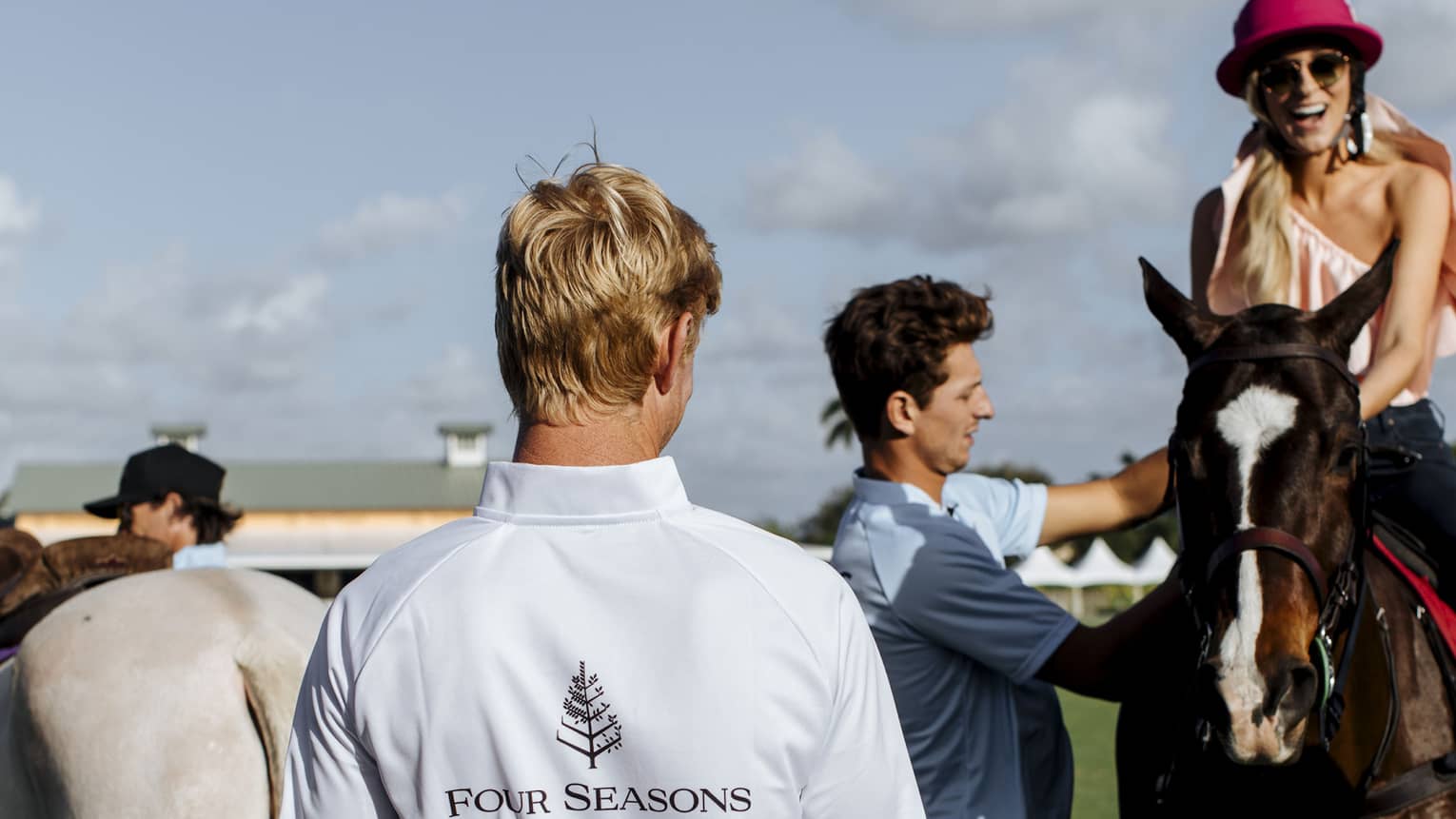 Back of polo player wearing uniform with Four Seasons and number 3, beside woman on horse